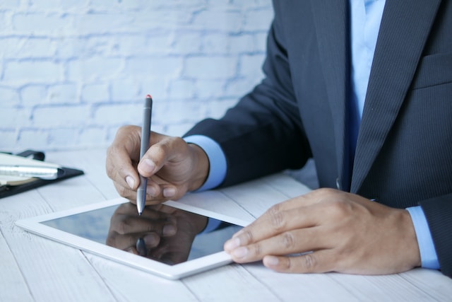 a man in a suit writing on a tablet
