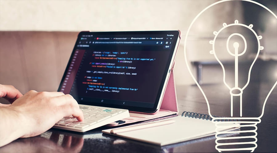 The core idea behind Infrastructure as Code laC - WeeTech Solution Pvt Ltd A person typing on a tablet keyboard with code on the screen and a lightbulb icon overlay.