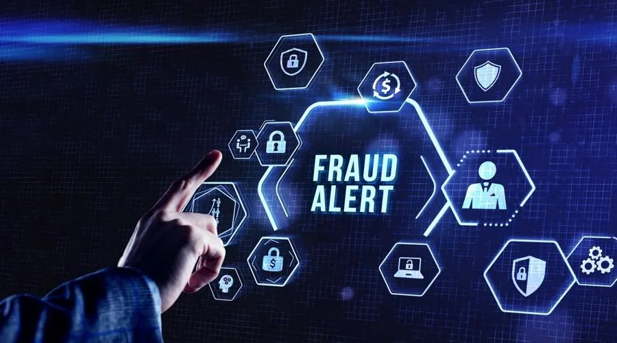A hand touching a digital interface screen displaying a "FRAUD ALERT" notification.