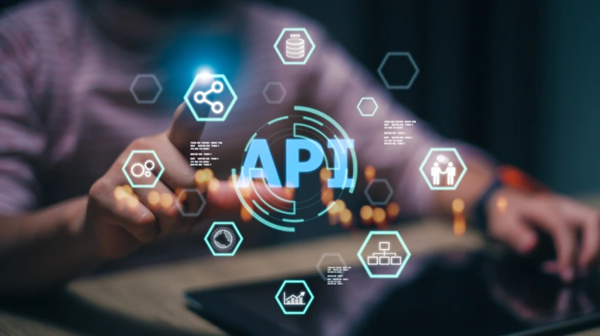 A hand interacting with a glowing holographic interface displaying tech icons around a central "API" logo.