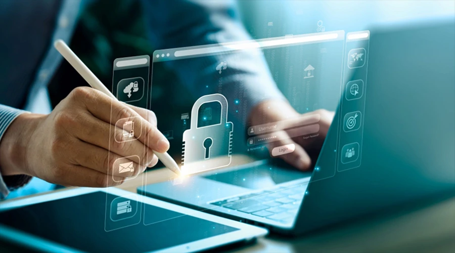A person using a stylus on a tablet next to a laptop displaying a prominent, glowing digital padlock on a security login interface.