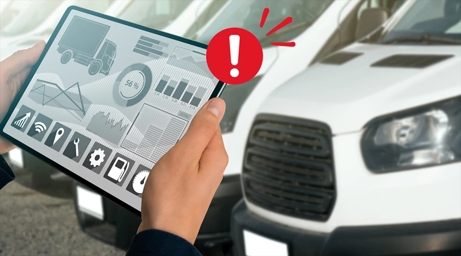 Vehicle Health Alerts - WeeTech Solution Pvt Ltd Hands holding a tablet that displays vehicle diagnostic graphs with a large red exclamation alert symbol next to a white van.