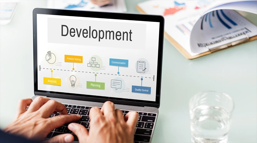 4. Cycode - best for broad SDLC posture in large development estates - WeeTech Solution Pvt Ltd A close-up of hands typing on a laptop screen that displays a "Development" roadmap breaking down different stages of the software lifecycle.